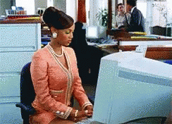 Mulher digitando na frente de um computador.